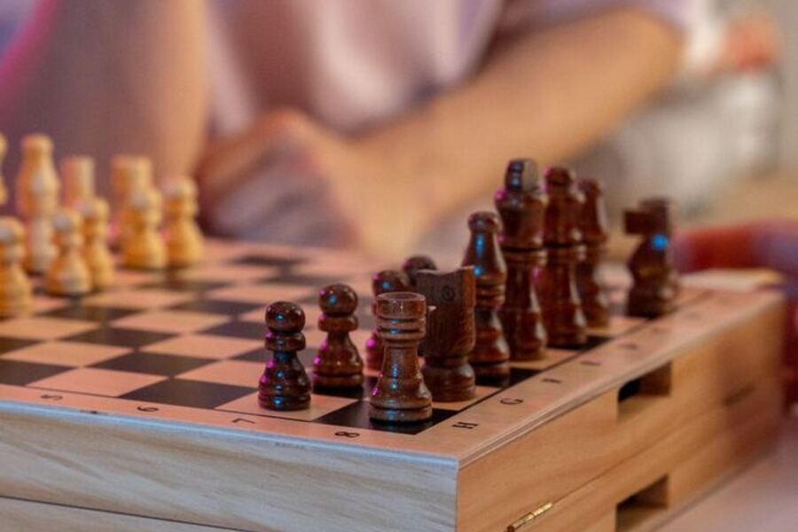 Manos sobre un tablero de ajedrez de madera, en plena partida.