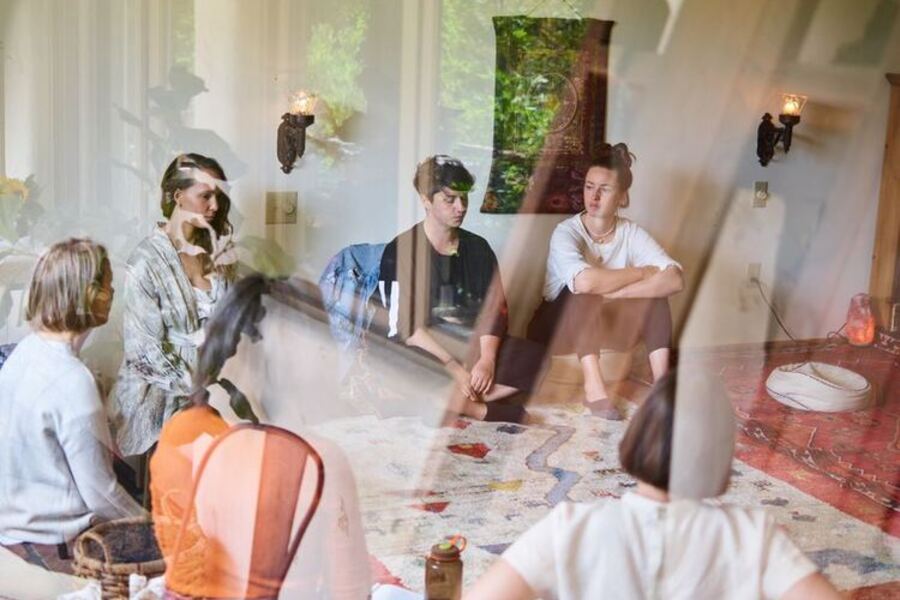 Círculo de personas compartiendo en una sala de luz cálida.