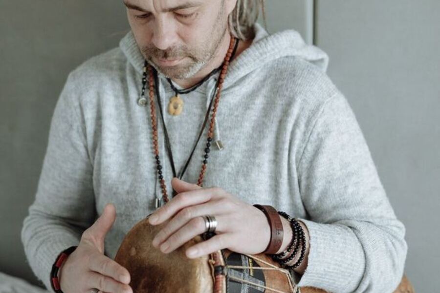Manos tocando un tambor de cuero, en primer plano.
