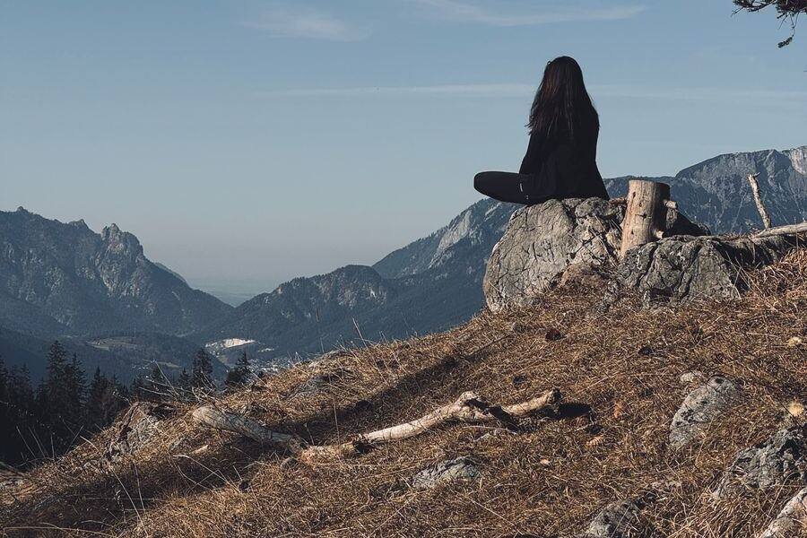Persona sentada sobre una piedra, mirando las montañas en silencio.